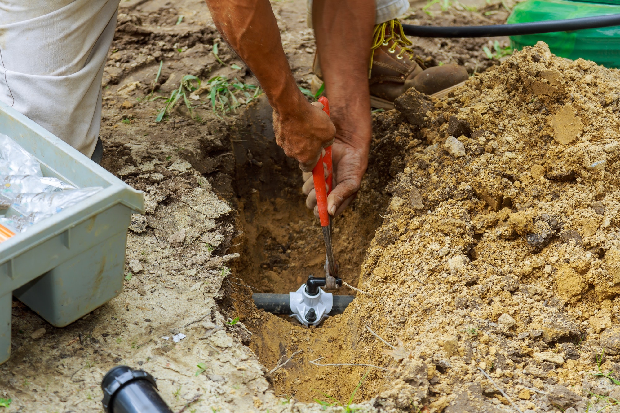 Underground Sprinkler System to Water the Yard Man Working with Pipes in Ground while Installing